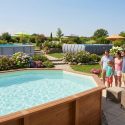 Une famille debout dans un jardin aménagé avec plusieurs piscines hors-sol de styles différents.